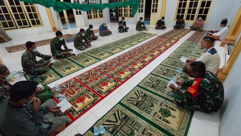 Anggota Satgas TMMD melaksanakan Yasinan bersama warga